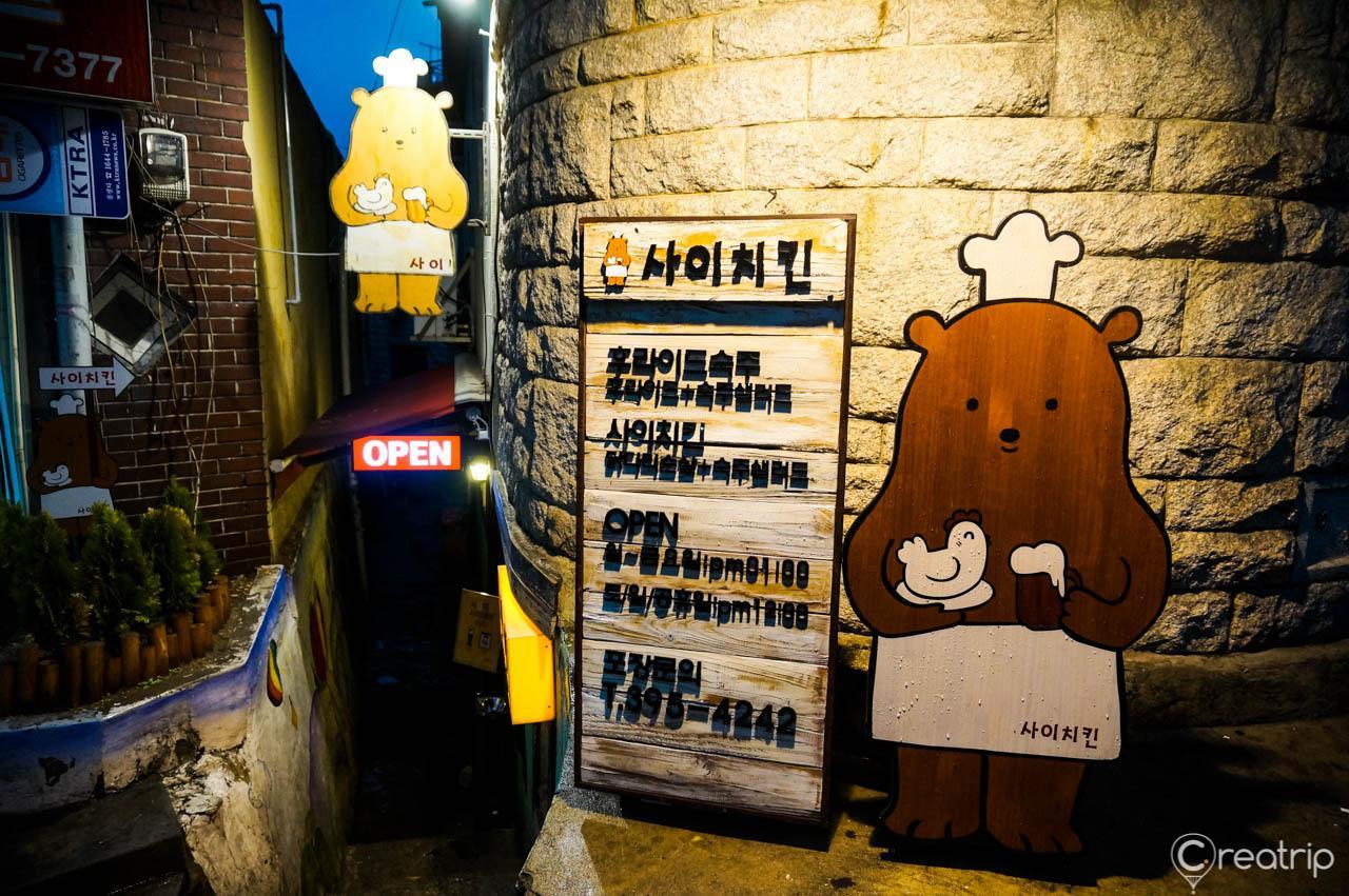 Yellow signage for 사이치킨 restaurant on a wooden facade advertising on a road in 부암동.