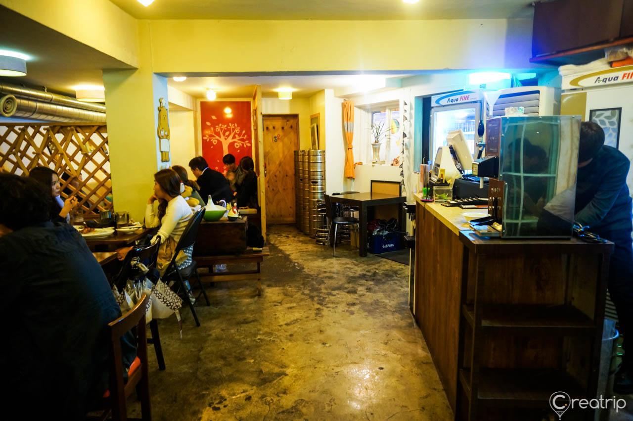 Interior of a Seoul restaurant featuring Saichi Chicken's signature dish with modern furniture, houseplants.