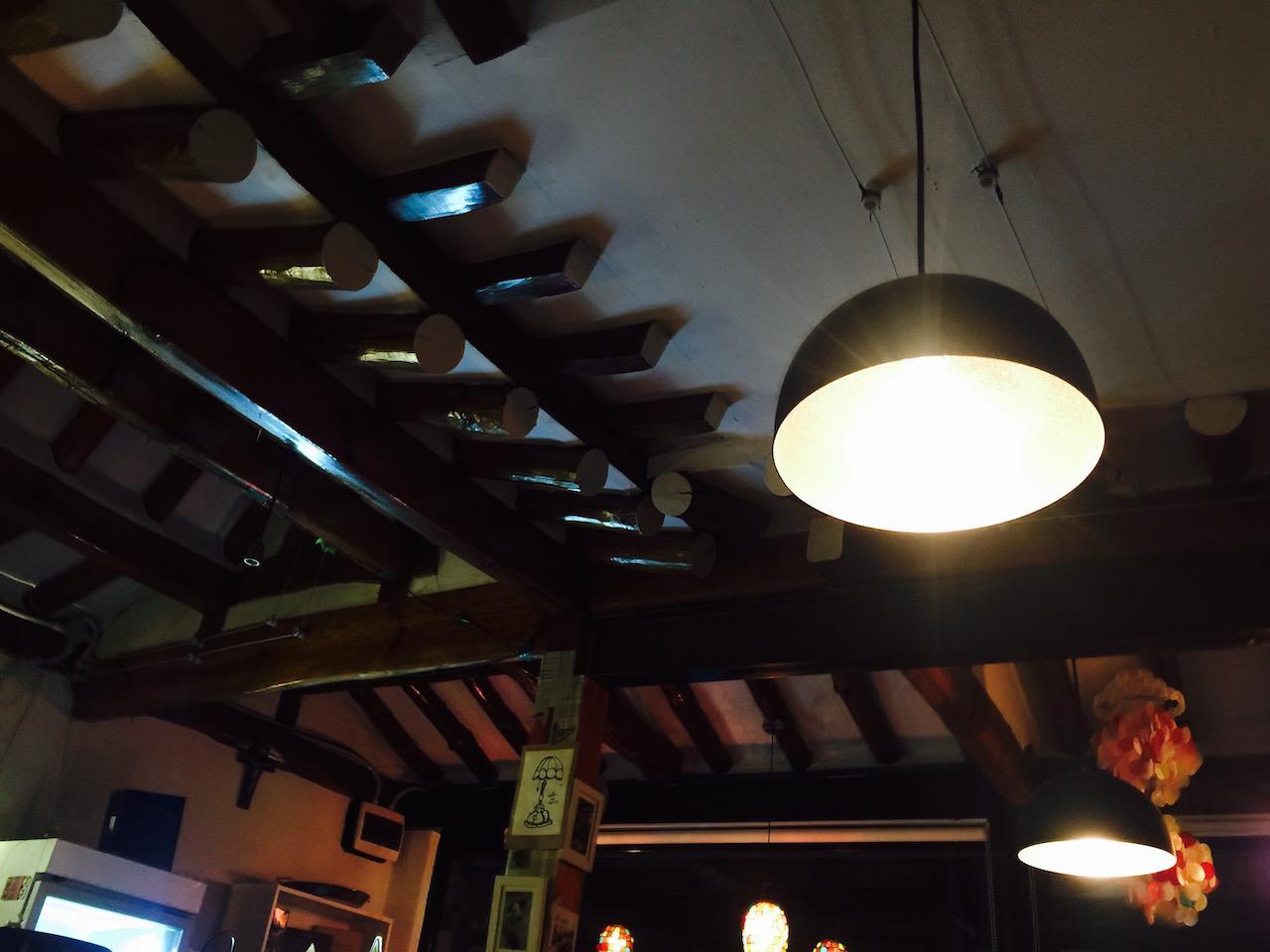 Ceiling fixture illuminating wooden beams in a building on Calle De Gomis; perfect for events.