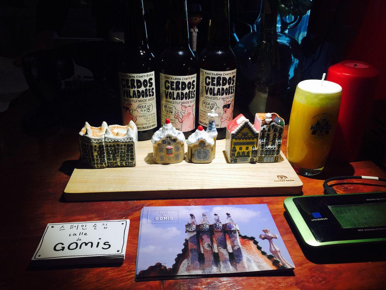 Bottle and glassware on a table at a scenic Korean restaurant in 서촌, with an artistic display of office supplies in the background.