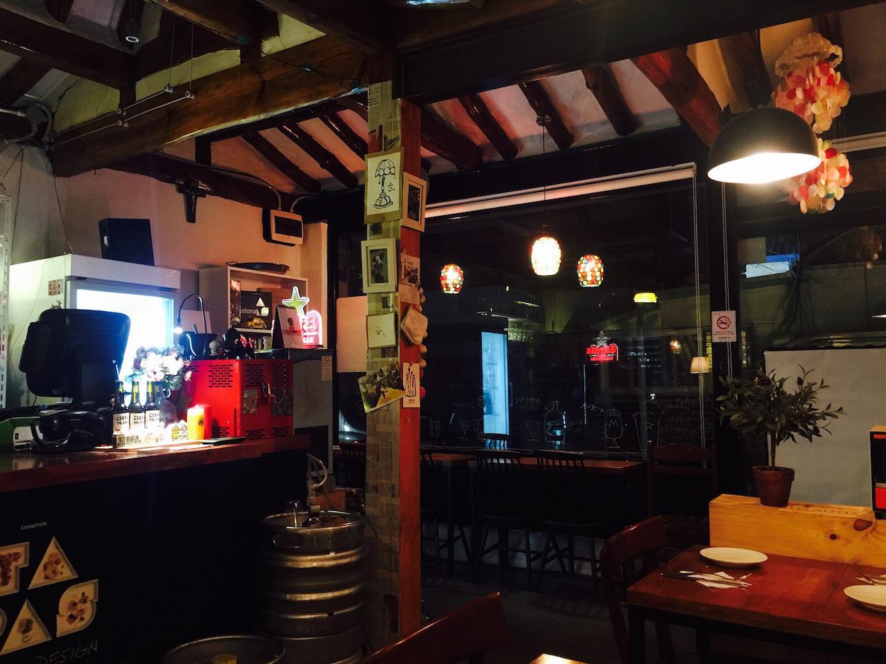 Interior of a bar in Seoul's Seochon neighborhood featuring tableware, barware, houseplants, and a television.