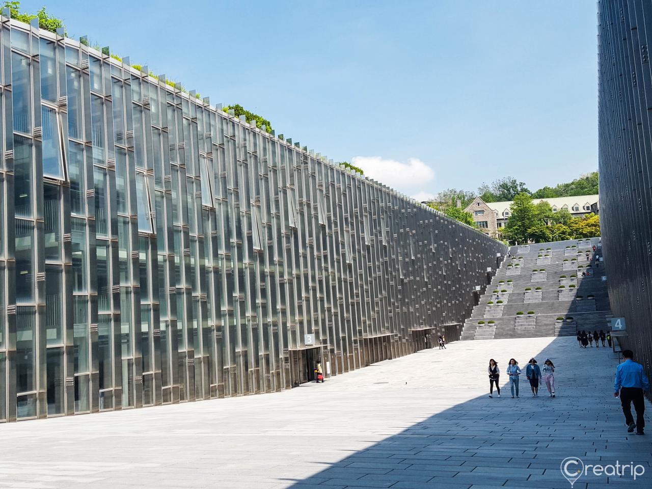 Urban skyline of Ewha Womans University campus with trees and cloud-filled sky.