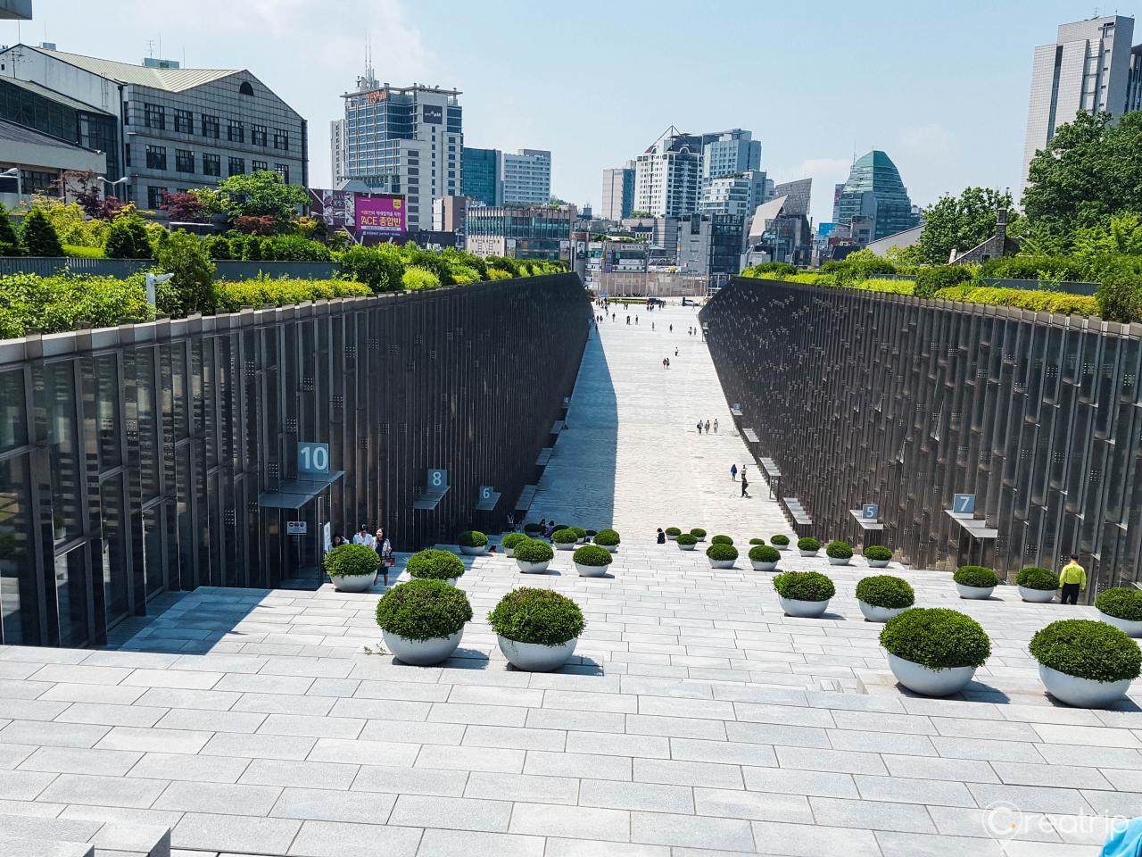 Urban landscape of Ewha Womans University, featuring a modern high-rise building, greenery, and tree-lined city streets.