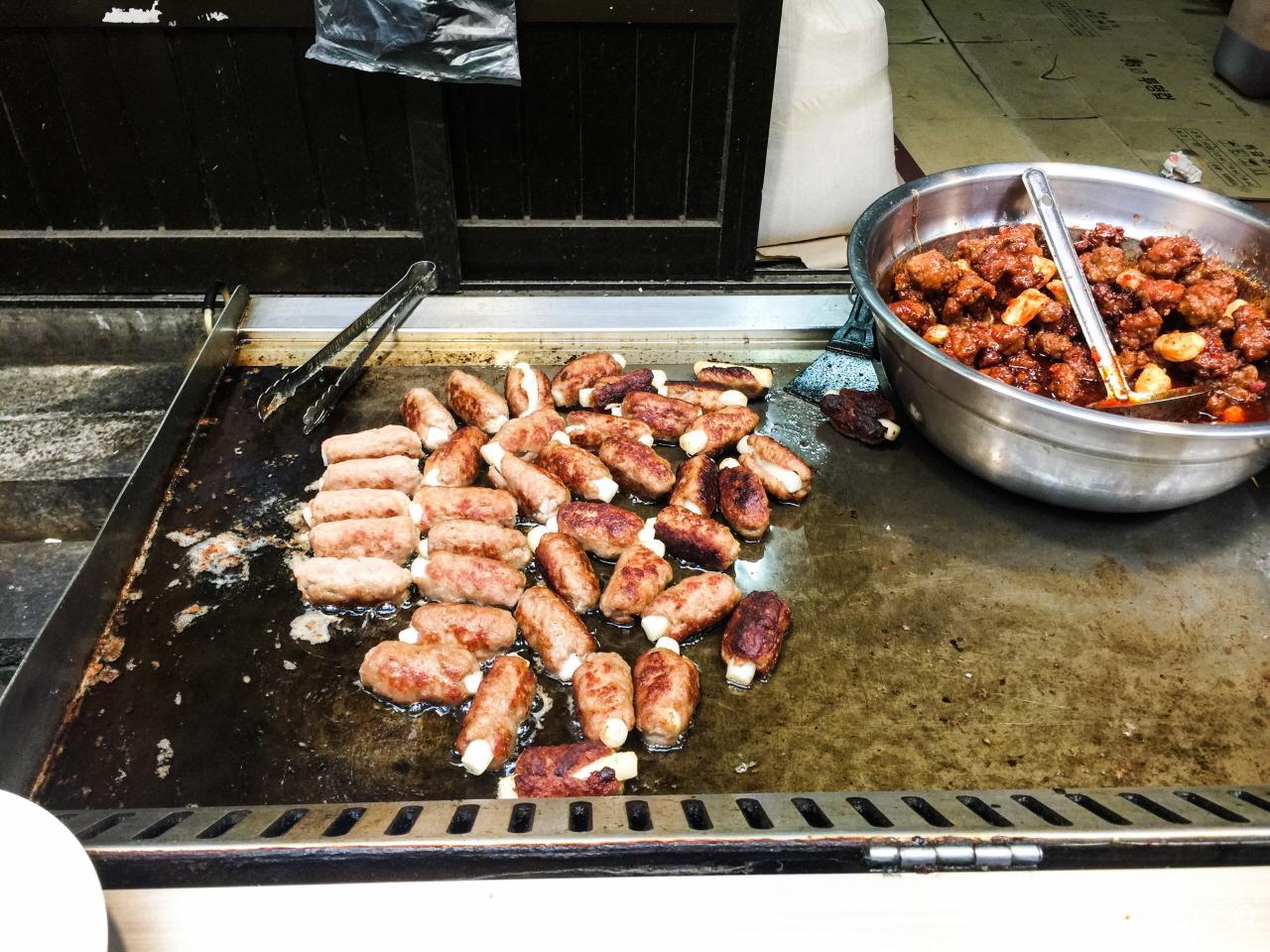 Roasting pork at the bustling Ttongin Market in Korea using a gas stove, for a delicious dish or ingredient.