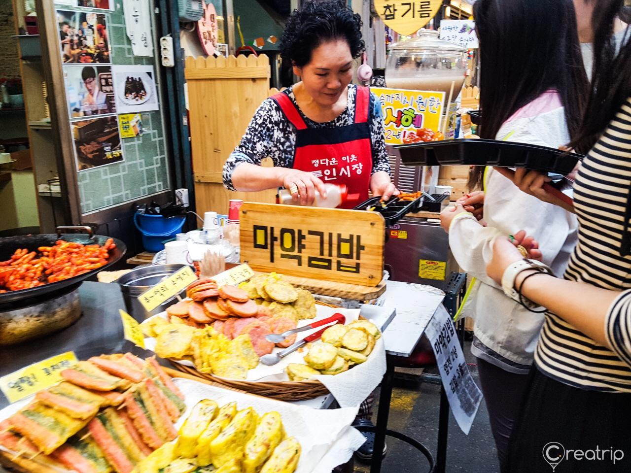 A bustling food market in Korea selling delicious, fast cuisine to eager customers.