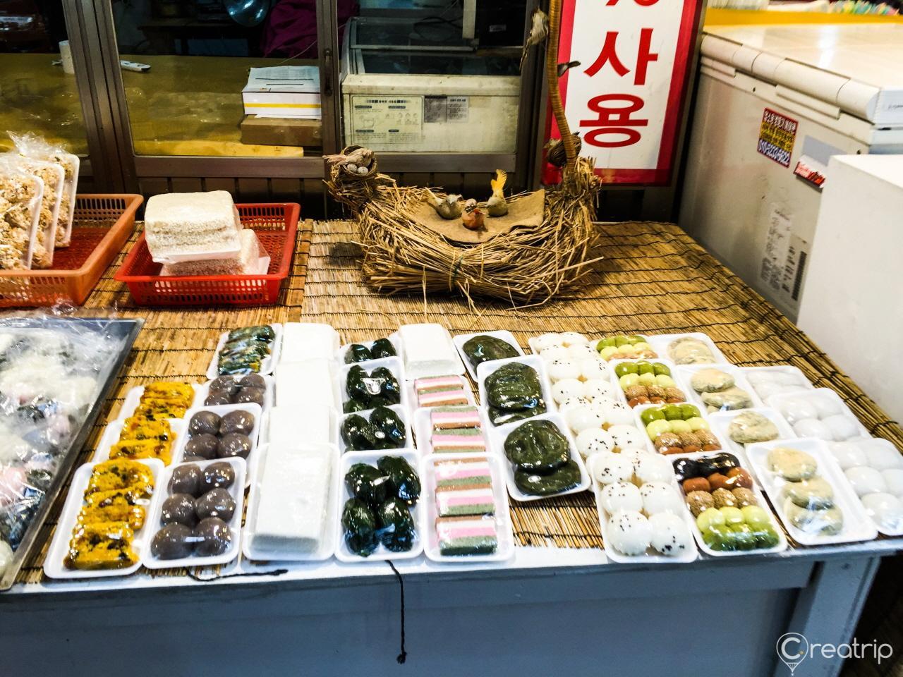 A colorful display of sweet and savory finger foods, ingredients, and whole foods at the bustling Tongin market in Korea.