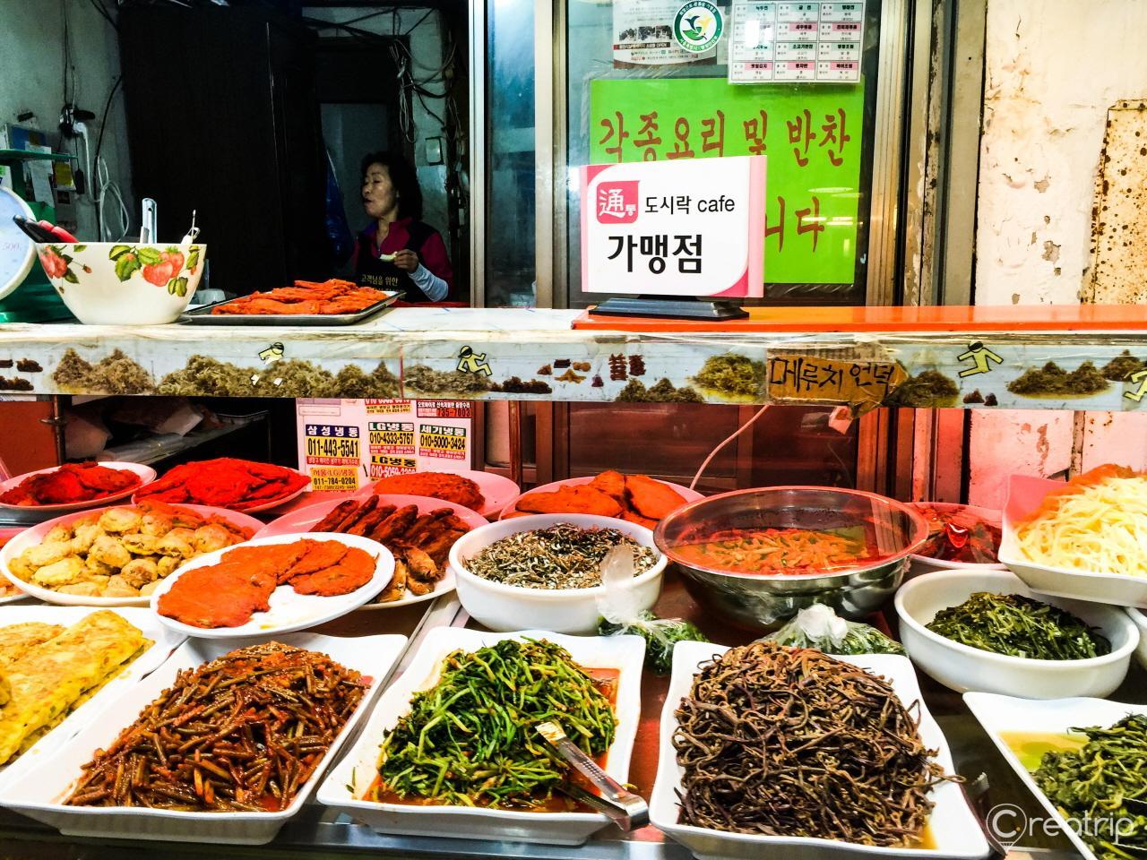 A tableful of fresh ingredients and dishes from 통인시장, showcasing Korean cuisine and natural, whole foods.