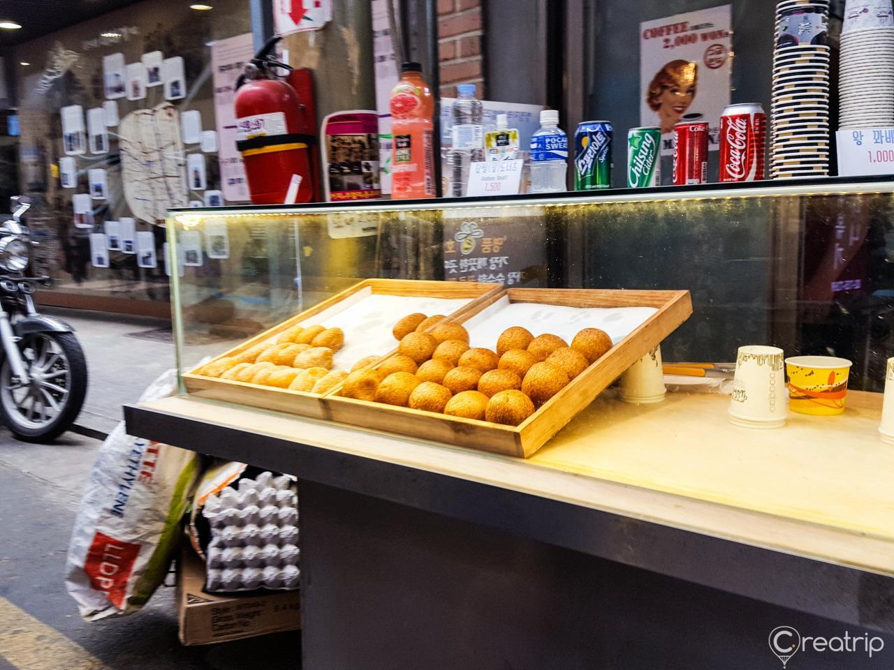 Delicious Korean street food at 통인시장 market; includes baked goods, finger foods, and delicacies on wooden tire wheels.