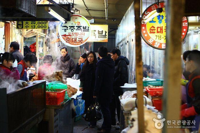 Busy public retail shops at 공덕족발골목, Korea. Customers shopping, selling, and trading in a bustling city market.
