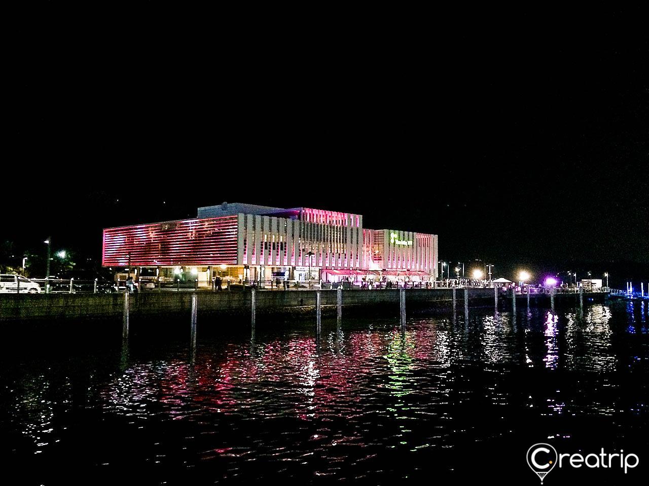 Nighttime skyline of Busan's vibrant city center, overlooking the illuminated Waterfront and 101 Tower amidst twinkling neon lights.