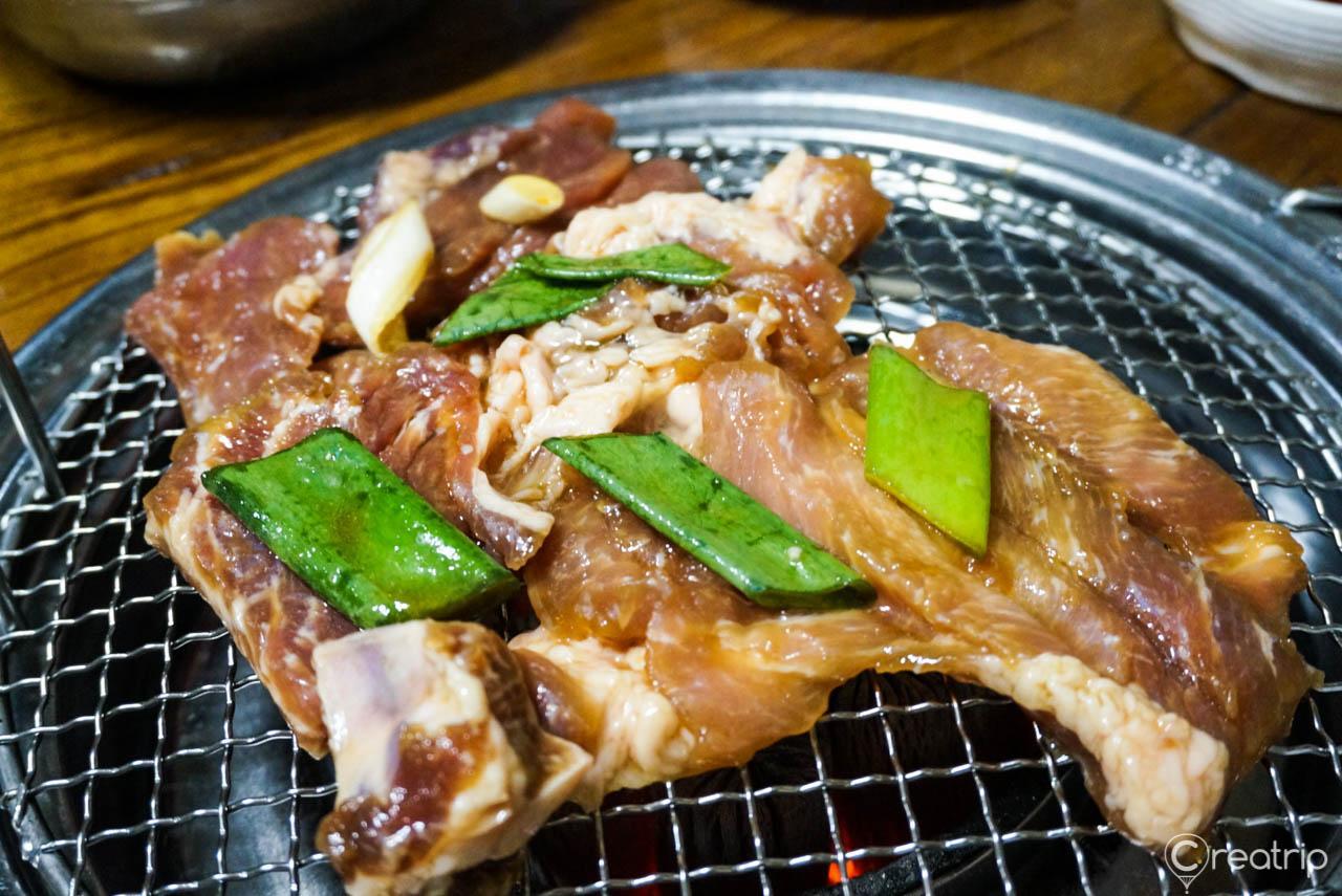 A delicious spread of Korean cuisine including 대성갈비, served on traditional tableware and serveware. Pork meat are featured prominently in the ingredients.