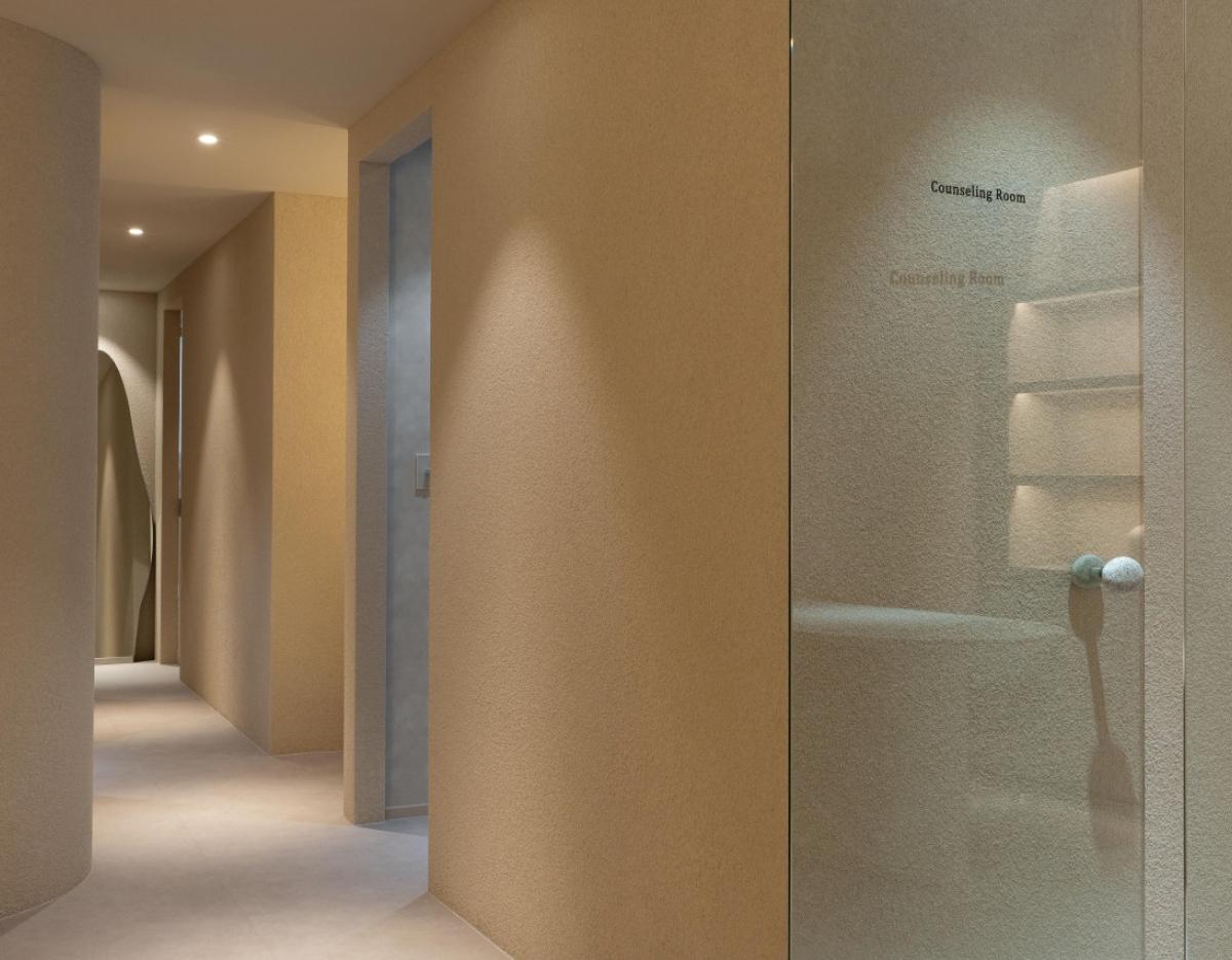 Minimalist beige hallway and textured glass door labeled "Counseling Room" inside a private esthetic clinic.