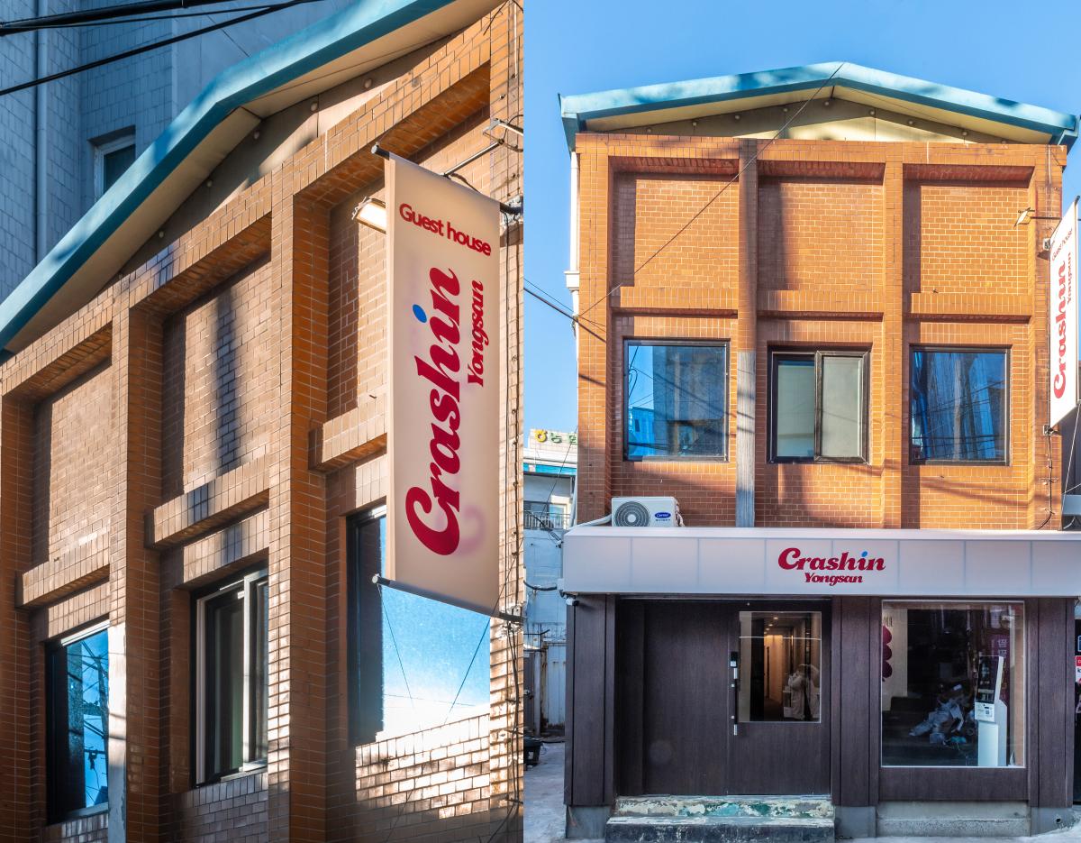 Three-story brick guesthouse with teal roof, vertical "Crashin Yongsan" banner and street-level entrance windows.
