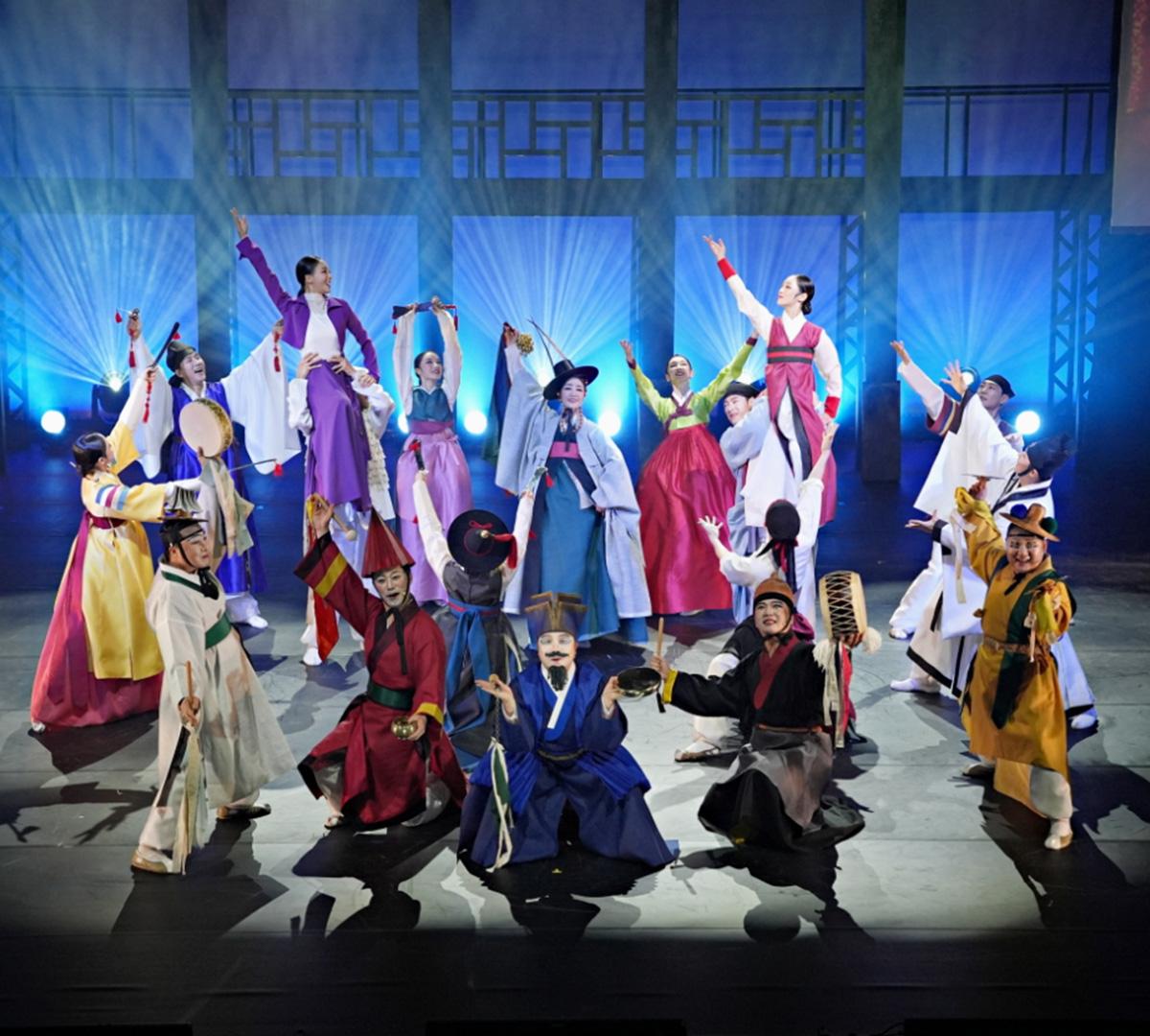 colorful troupe of Korean traditional performers in hanbok and masks mid-dance on stage at Seoul Jeongdong Theater