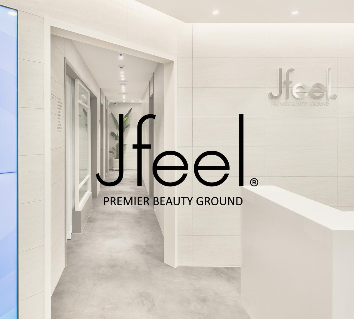 Minimalist clinic reception and hallway with white walls, gray floor, potted plant, and large "Jfeel Premier Beauty Ground" logo.