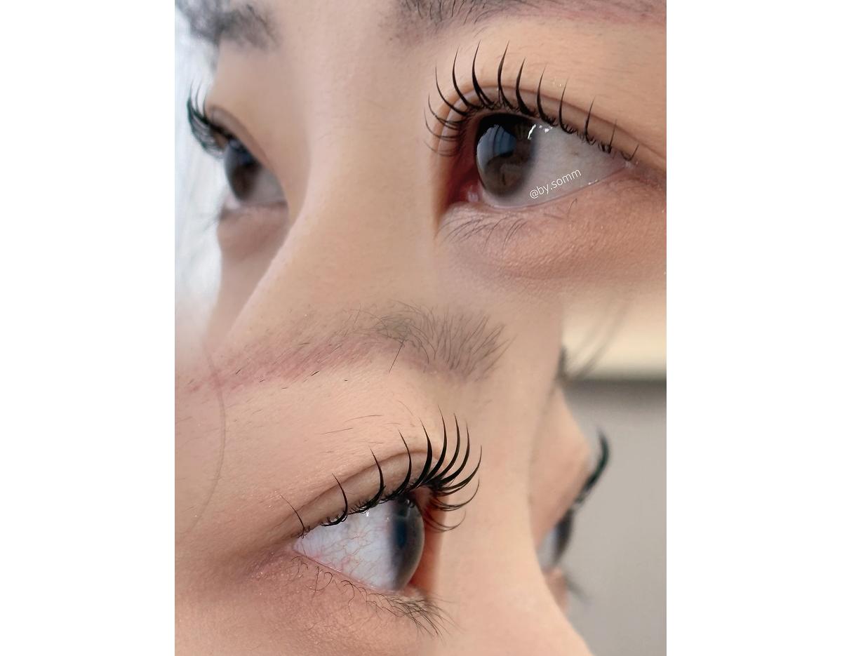 close-up of two angled eyes with long, lifted curled lashes after lash lift and black tint, natural skin detail visible