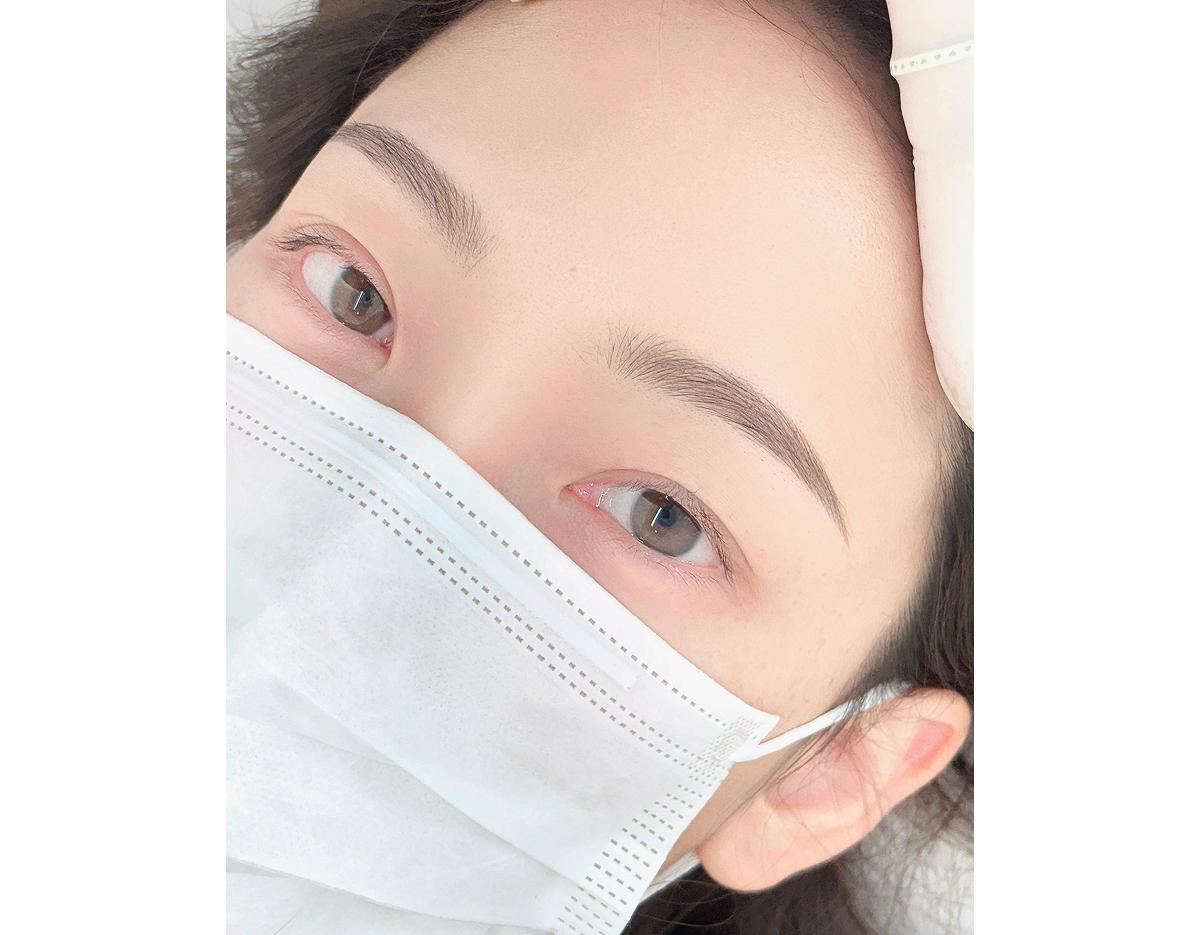 close-up of freshly microbladed hairstroke eyebrows on a masked person, natural neat arch and fine hair strokes