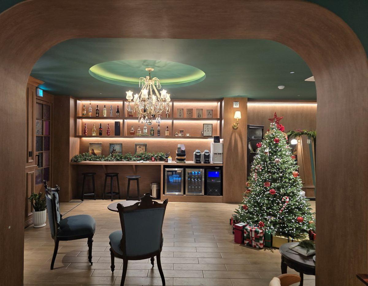 arched retro lounge with chandelier, minibar shelves, vintage chairs and decorated Christmas tree with wrapped gifts