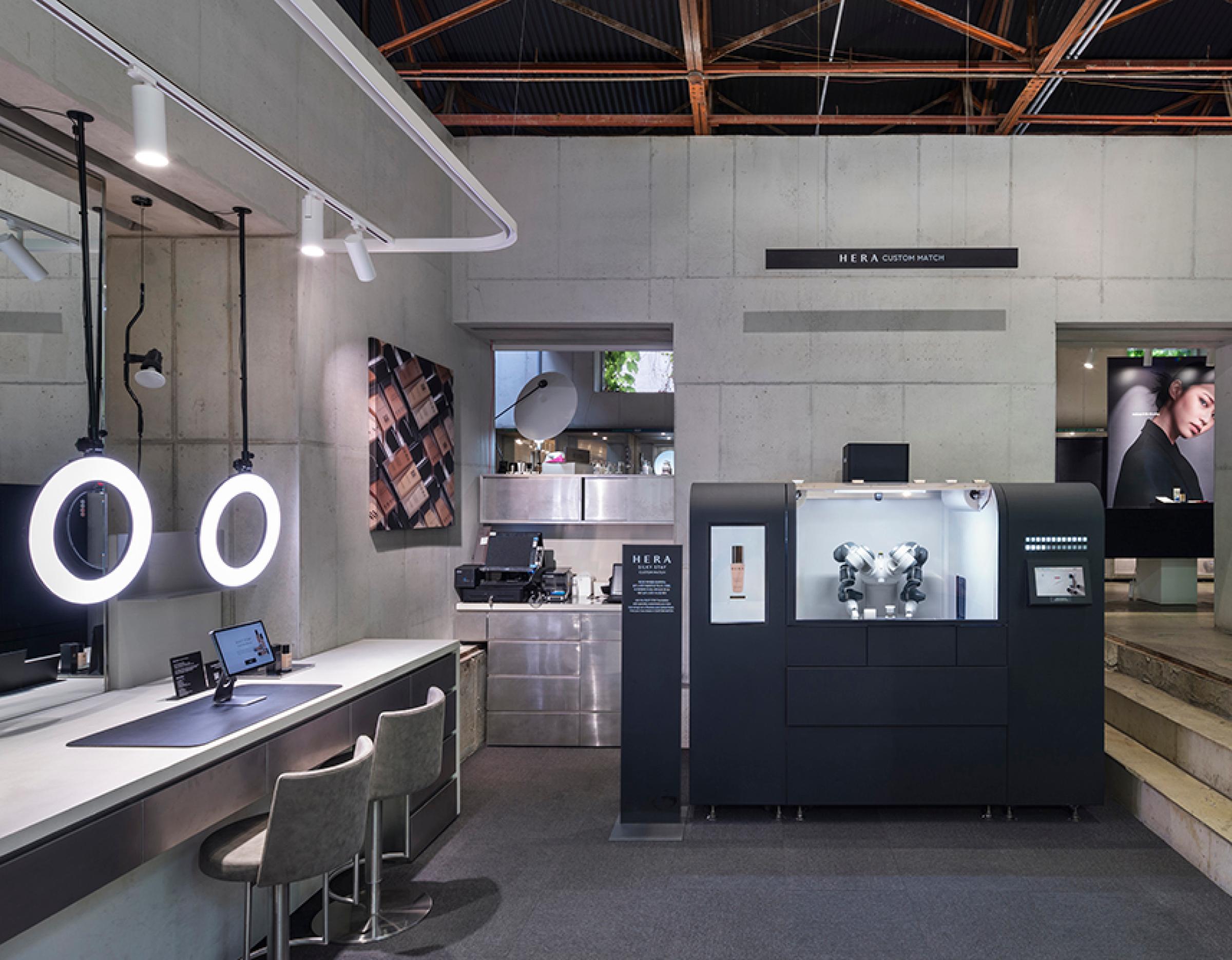 HERA custom match station with robotic dispenser, concrete walls, ring lights and seating in a sleek Seoul beauty studio