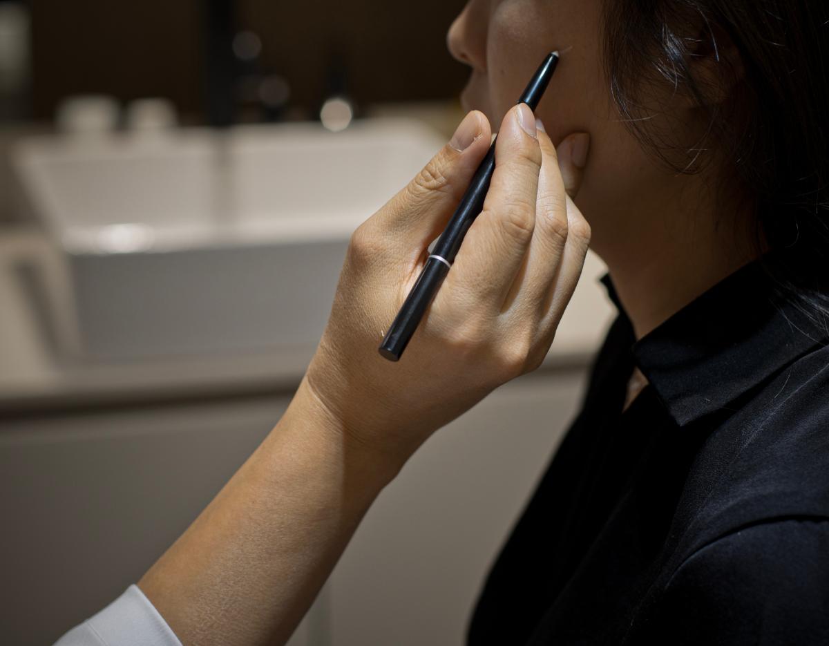 Doctor holding a white microneedling device near a patient's chin during a facial treatment at the clinic.