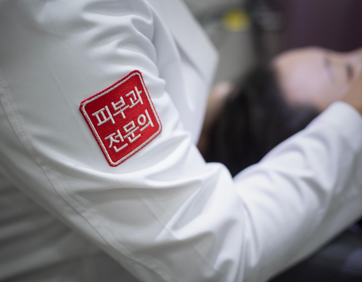 white doctor's sleeve with red patch reading "피부과 전문의" (dermatology specialist) at 마포 타임리스피부과 clinic