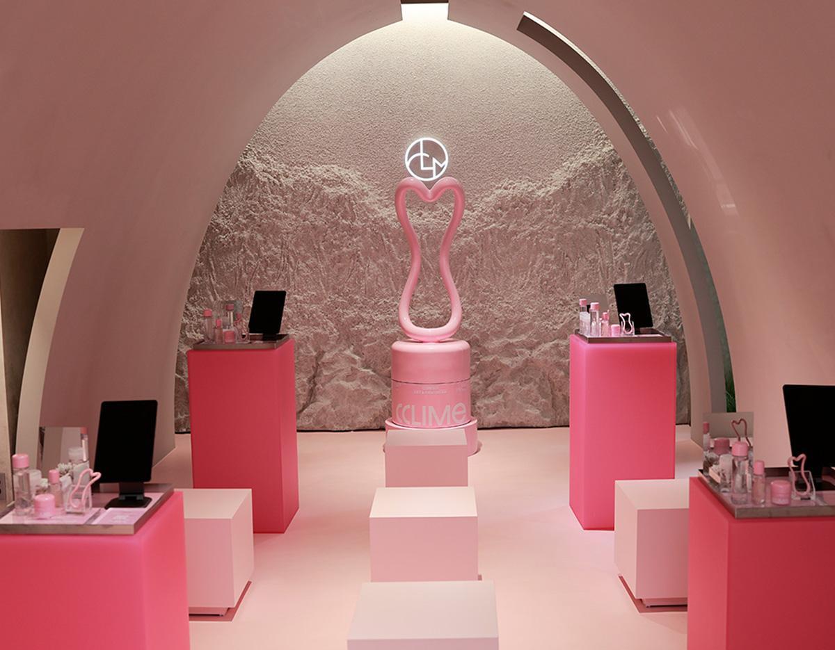 therapist's hands holding a gold dual-ball facial massage tool against a client's jawline on a treatment bed