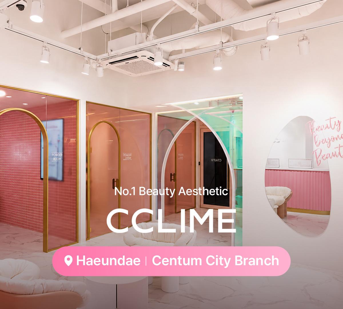 therapist's hands holding a gold dual-ball facial massage tool against a client's jawline on a treatment bed