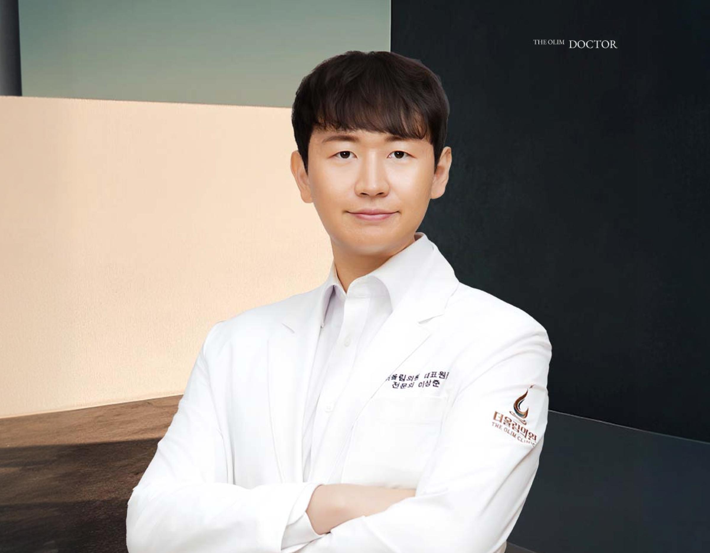 흰 가운을 입고 팔짱 낀 의료진 상반신, 가운 소매에 더올림의원 로고와 가슴 앞 이름 자수 보임