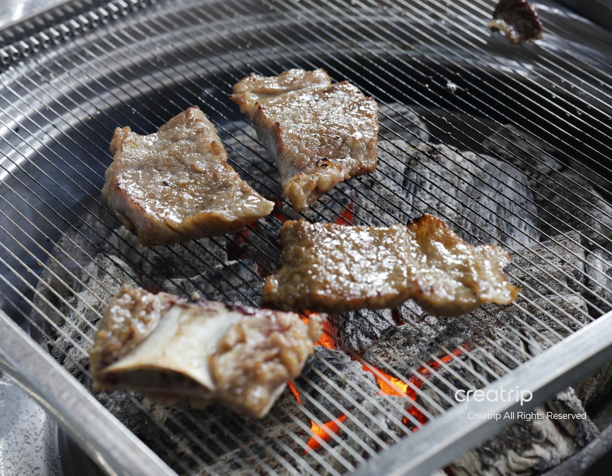 Charcoal grill with glistening marinated galbi and short rib pieces searing over hot embers at Cheonggiwa Galbi, Hongdae.