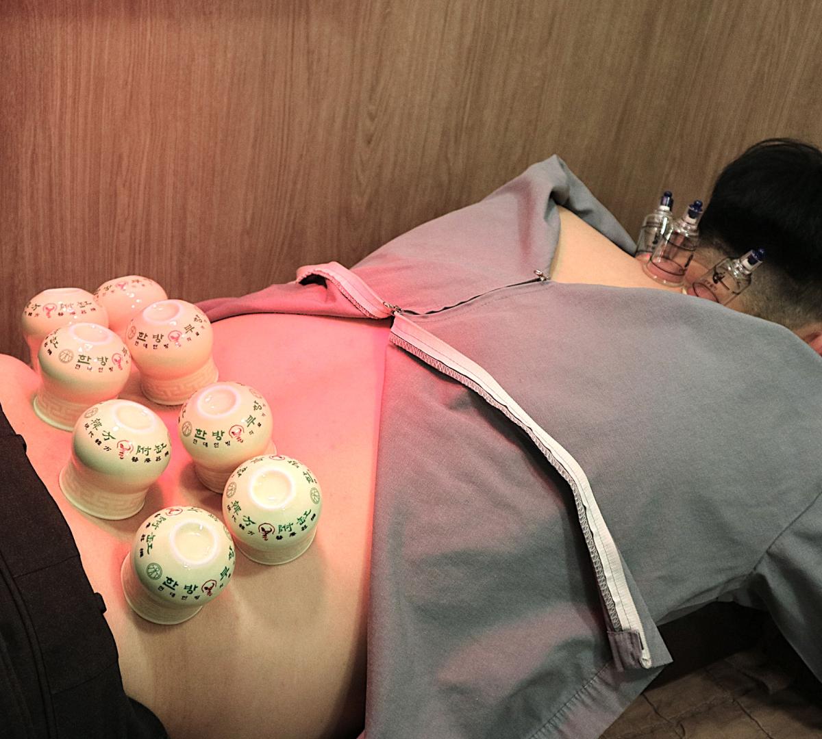 Patient reclining on treatment chair receiving a female practitioner’s hands-on neck adjustment at 케이한의원 | USP clinic.