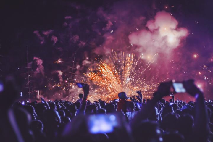 Crowd at 2026 KMCHART AWARDS watching bright orange fireworks and purple smoke, several audience members holding up phones.