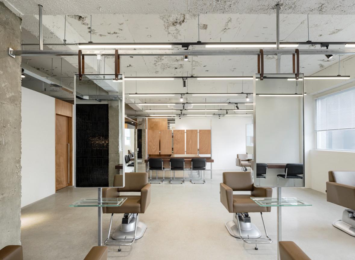 로위 성수블랙점 salon interior with minimalist concrete ceiling, brown styling chairs and glass side tables in bright space
