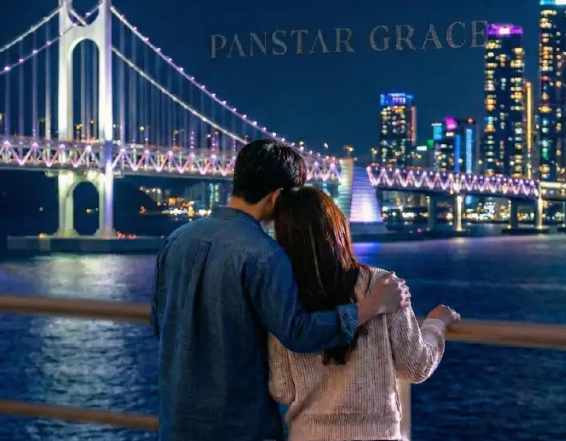 couple embraced on a yacht deck at night gazing toward illuminated Gwangan Bridge and city skyline reflections