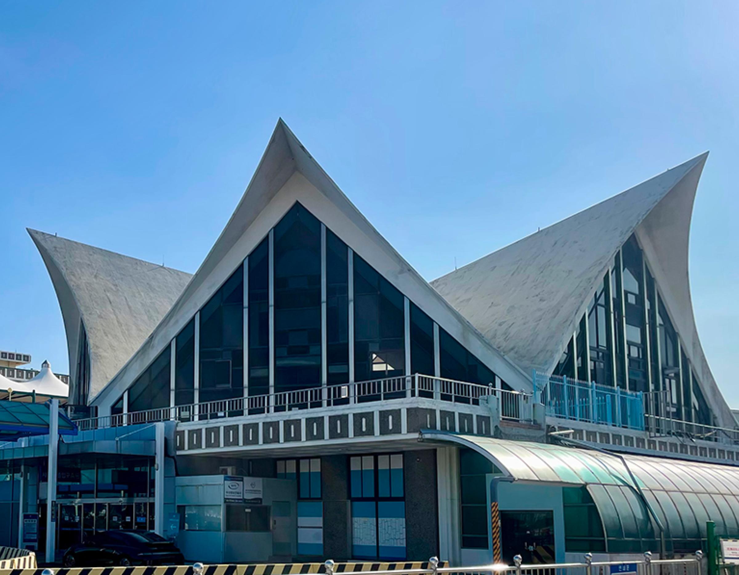 Busan superyacht terminal building with sweeping white curved roof peaks and glass facade under clear blue sky