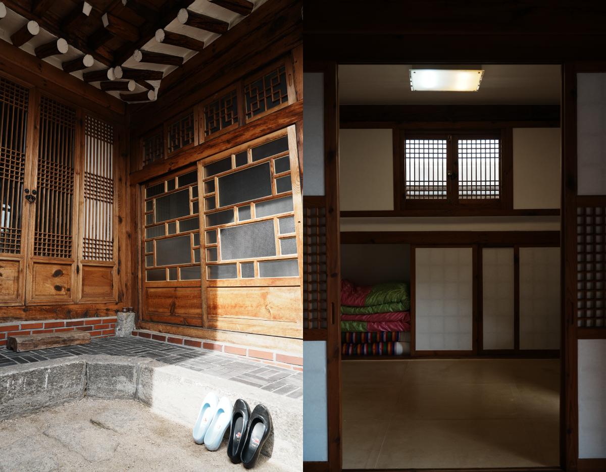 Traditional wooden hanok entrance with patterned sliding doors, stacked bedding visible through inner room, shoes at step