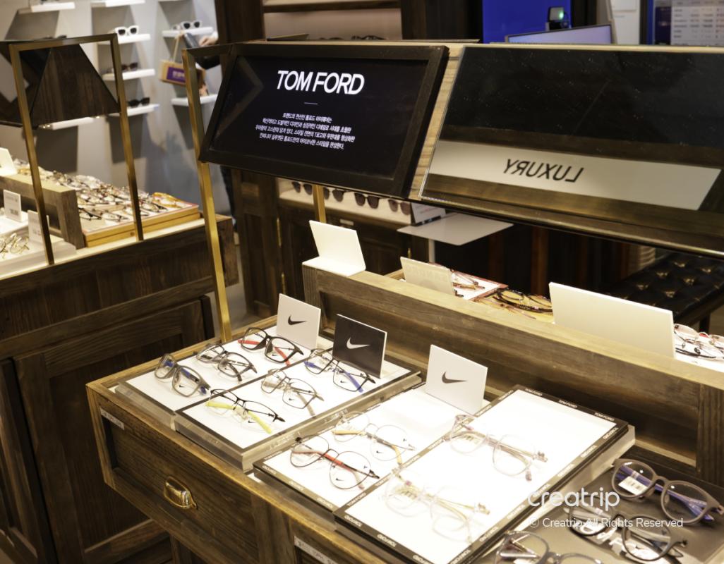 Tom Ford and Nike eyewear display on wooden counters at 룩옵티컬 강남역점, rows of trendy eyeglass frames and mirrors