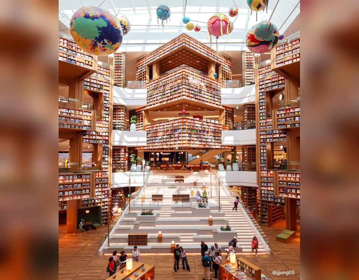 Starfield Suwon Byeolmadang Library interior with towering honeycomb bookshelves, central stepped seating, and hanging globe art.