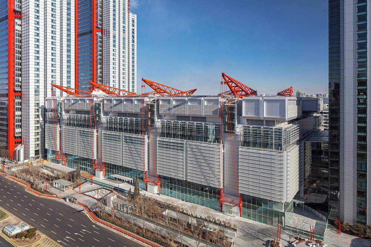 Modern multi-level glass and metal Hyundai Seoul Yeouido Pass building with red structural cranes on rooftop beside tall towers.