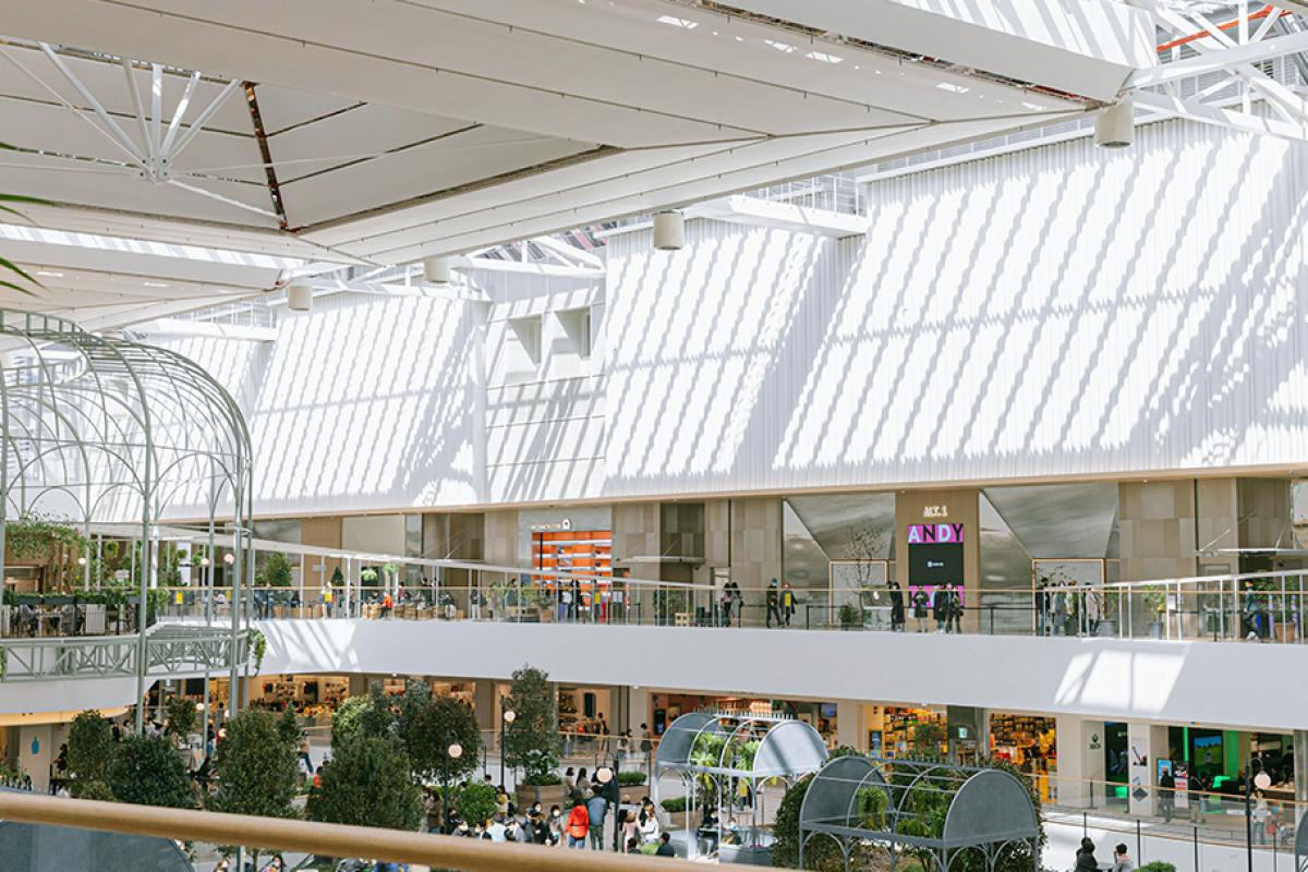 Spacious sunlit atrium at THE HYUNDAI SEOUL YEOUIDO PASS with multi-level walkways, greenery, arched metal pergolas and shoppers below