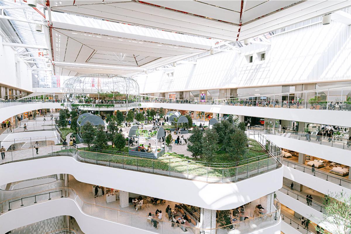 Spacious multi-level atrium at THE HYUNDAI SEOUL YEOUIDO PASS with central elevated garden, trees, seating pods and skylights