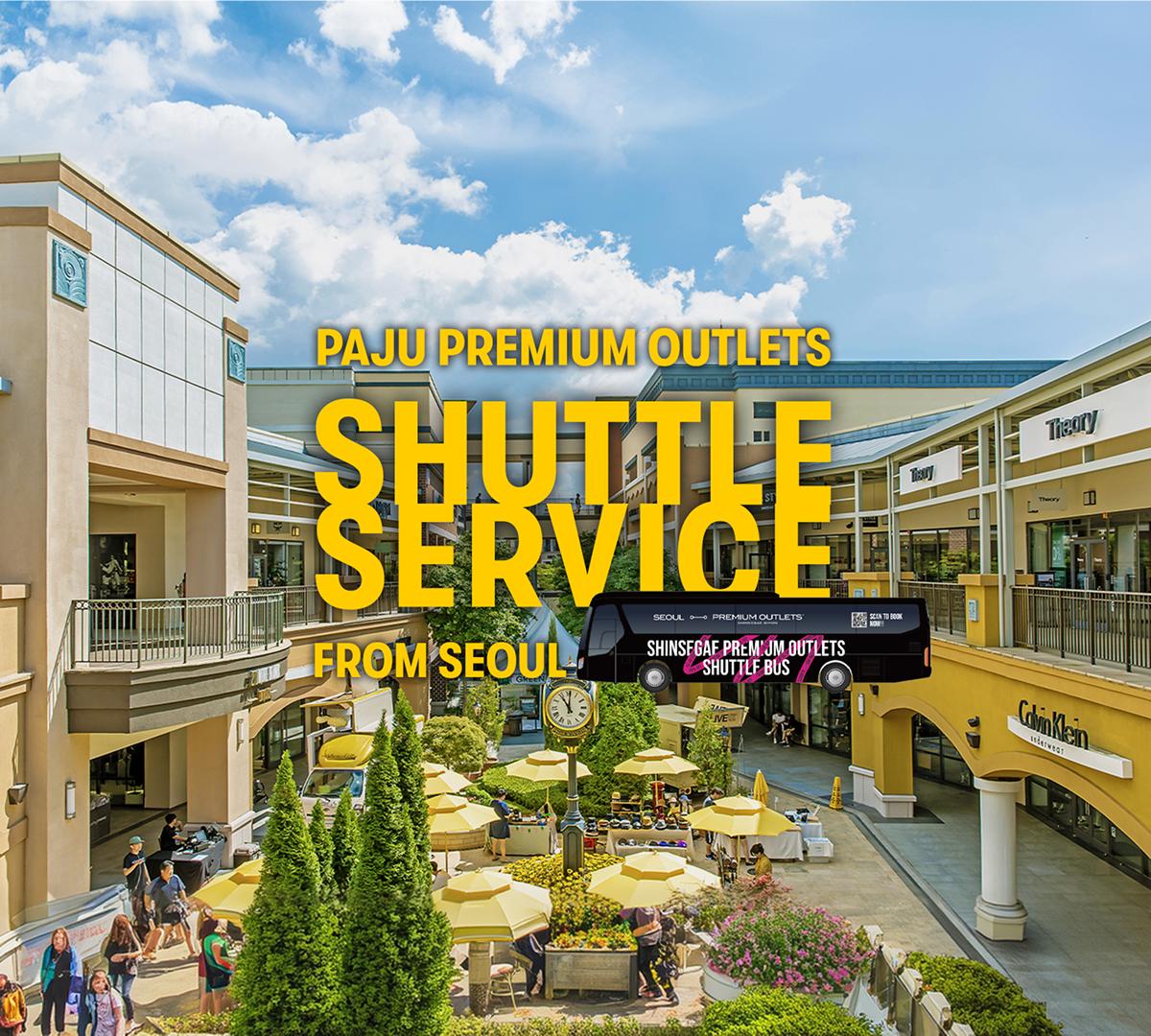 Outdoor view of Paju Premium Outlets courtyard with yellow umbrellas, shoppers, storefronts and bold "Shuttle Service" text overlay.