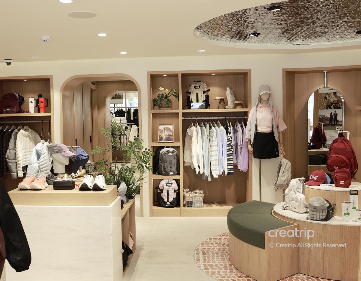 Well-lit The North Face HANNAM store interior with wooden shelves, backpacks, jackets, shoes and a mannequin dressed in casual activewear