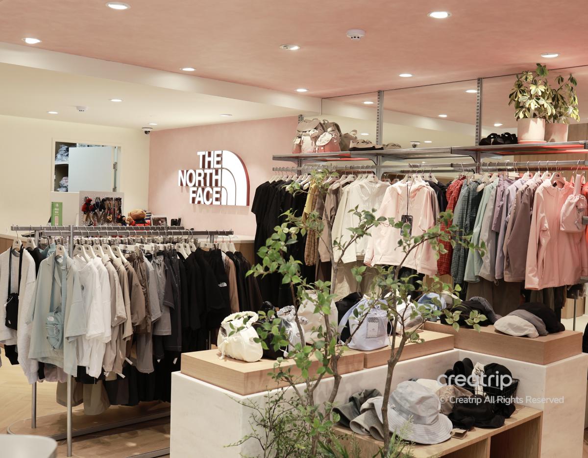 No Faced The North Face HANNAM store interior with racks of pastel jackets, shirts, backpacks and hats displayed around potted plants
