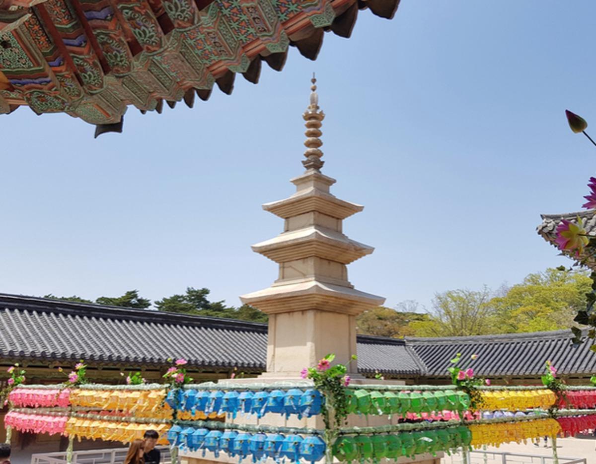 Stone pagoda at Bulguksa temple courtyard framed by ornate eaves and rows of colorful lotus lanterns