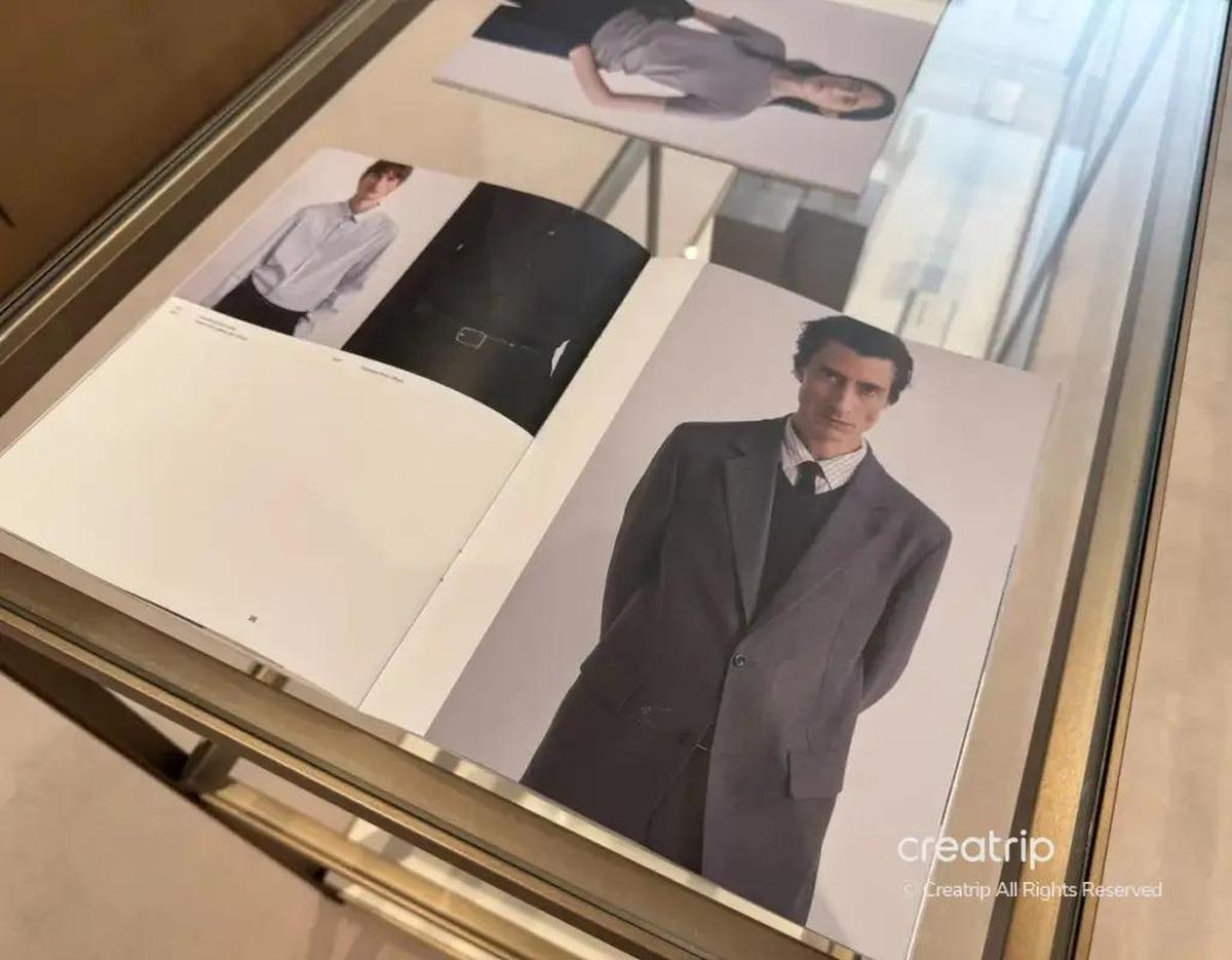 open lookbook on glass table showing men's tailored blazer outfit and small photos of shirts and models