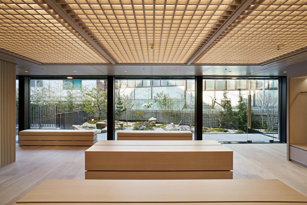 Pottery Hannam interior with minimalist light wood benches, grid-lit ceiling and floor-to-ceiling windows overlooking a small Japanese-style garden
