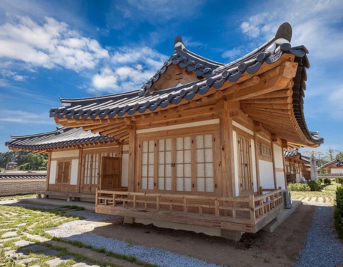 Traditional wooden hanok guesthouse at Ojuk Hanok Village with curved tiled roof under blue sky