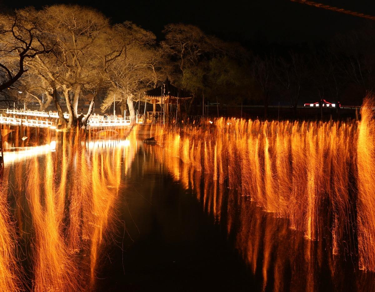 Golden traditional Nakhwa Nori sparks reflected on the water at Mujinjeong Pavilion