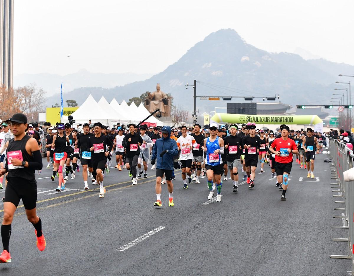 Participants running on a Seoul city road with mountains in the background