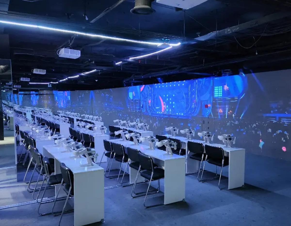 K-Culture VR Tower VR theater rows of desks with 4K VR headsets and chairs facing a long panoramic concert projection wall